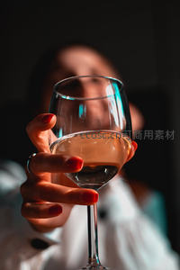 红甲女子手持红酒杯，逆光剪影与通透酒液的优雅特写
