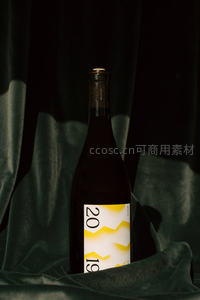 深色丝绒背景下的2019年份葡萄酒瓶特写，光影交错显高级质感