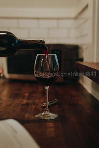 厨房木质吧台上红酒正倾入高脚杯，动态飞溅瞬间捕捉生活仪式感
