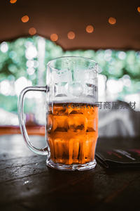 冰镇啤酒扎杯特写：气泡凝结水珠，背景虚化绿意与暖光点缀