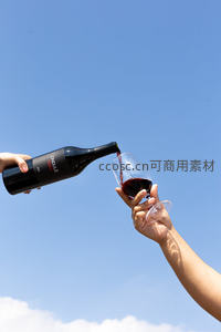 蓝天之下倾注赤霞：红酒从瓶中注入高脚杯的优雅瞬间