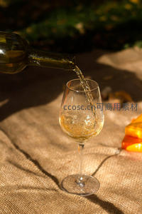 阳光下白葡萄酒缓缓注入亚麻布上的高脚杯