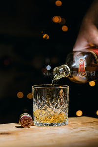 夜色中琥珀威士忌倒入雕花水晶杯，红标酒盖静置一旁