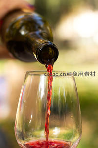 户外自然光下红酒注入高脚杯，红色酒液如丝滑落