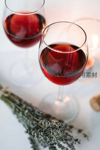 两杯红酒配干薰衣草束，烛光映照下静谧优雅的品酒时刻