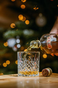 圣诞夜琥珀色威士忌倾倒入雕花玻璃杯，背景暖光闪烁如星