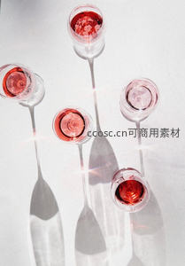 俯拍五只高脚杯盛玫瑰红葡萄酒，光影交错创意构图