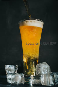 金黄啤酒倾注入高脚杯，冰块环绕，气泡升腾的动感特写