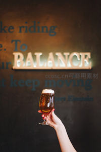 手持精酿啤酒杯置于‘BALANCE’霓虹灯墙前，传递健康生活理念