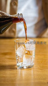 深褐色碳酸饮料倾入冰块玻璃杯的特写瞬间