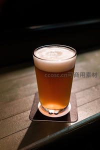 精酿啤酒特写：泡沫丰盈的IPA置于木质吧台暖光之下