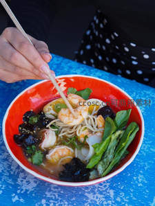 红碗虾仁面配木耳青菜，手执筷子正夹起鲜虾入味汤底