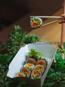 竹筷夹起彩虹卷寿司，纸盒装日式外卖配绿植点缀清新自然