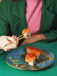 女士手持三文鱼寿司卷，蓝釉瓷盘装饰精致，职场女性午餐时刻
