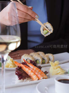 筷子夹起芝麻脆皮寿司卷，配甜虾与姜片，白葡萄酒佐餐