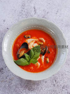 番茄海鲜浓汤盛于青瓷碗中，贻贝虾仁点缀罗勒叶，清新雅致