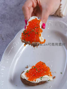 手握鱼子酱吐司，橙红鲟鱼籽覆奶油奶酪，指尖粉甲增添优雅细节
