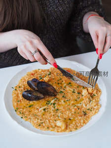 海鲜意式烩饭特写：青口贝点缀金黄米饭，手部用餐瞬间