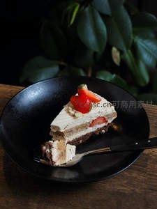 黑碗中的草莓杏仁蛋糕切片，叉子轻挑展现层次