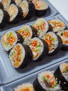 韩式紫菜包饭切片特写，内馅丰富含虾仁蔬菜芝麻，灰盘盛放