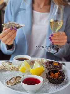 生蚝海胆拼盘配香槟，女士手持生蚝与酒杯，冰镇海鲜盛宴