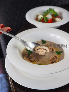 奶油蘑菇浓汤盛于白碗，银勺舀起菌菇片点缀欧芹
