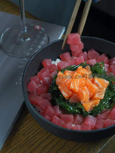 筷子夹起金枪鱼poke bowl，玻璃杯与菜单背景