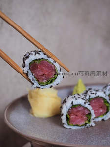 筷子夹起金枪鱼手卷，芝麻海苔包裹鲜嫩鱼肉，配姜片与芥末，日式精致料理