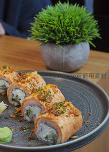 精致三文鱼寿司卷配葱花脆片，灰釉盘盛装，背景绿植点缀
