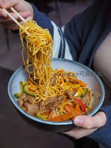 筷子高举炒面特写，碗中肉片彩椒拌面香气扑鼻，暖调居家风
