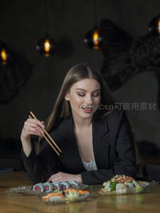 优雅女性用筷子夹寿司，面前摆放多款日式料理