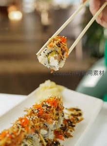 筷子夹起金丝蟹柳寿司卷，芝麻海苔点缀的创意日料特写