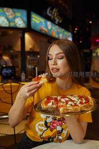 年轻女子手持披萨托盘，闭眼品尝意式薄底披萨的惬意瞬间