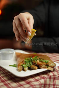 手捏柠檬汁滴落炸鱼卷，特写展现鲜香瞬间与精致摆盘