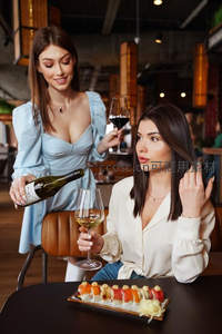 侍酒师为顾客斟倒白葡萄酒，桌上寿司与互动瞬间