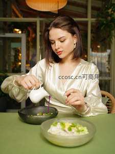 女士专注为两道前菜淋上紫色酱汁，丝质衬衫映衬餐厅温馨氛围