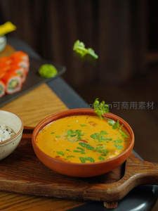 泰式咖喱汤配香菜与寿司卷木盘摆拍