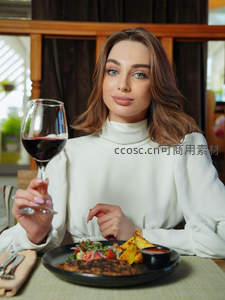 优雅女士举红酒杯享烤肉沙拉套餐