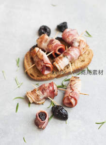 培根卷梅干小食摆盘，搭配迷迭香与烤面包片，精致开胃前菜