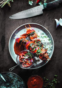 印度风味烤肉串配椰香米饭与莎莎酱，刀具点缀暗调桌面