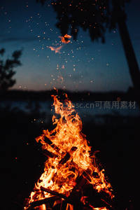 暮色湖畔篝火升腾，火星如星雨洒向夜空