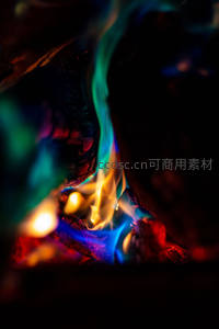 微距视角下彩色火焰在木炭间舞动，蓝绿黄红交织梦幻
