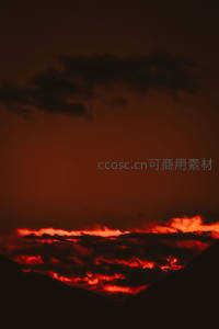 山峦剪影间赤红云层翻涌，如熔岩倾泻的壮丽晚霞奇观