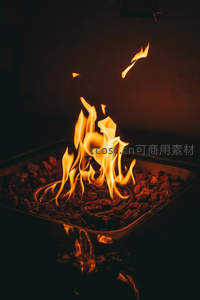 跳动的篝火余烬：火苗在熔岩石上轻盈舞动，倒影映衬幽暗空间