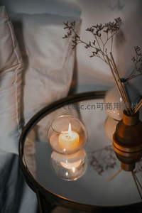 玻璃茶几上烛光摇曳，干花香薰与柔软床品营造静谧卧室氛围