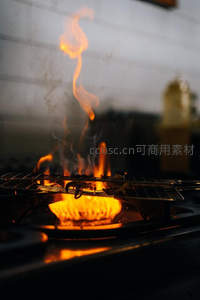 燃气灶明火炙烤食材，铁网下火焰升腾烟雾缭绕，厨房烹饪动态抓拍