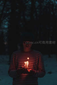 雪夜中少年捧烛凝望，微光映照条纹衫与沉静面庞