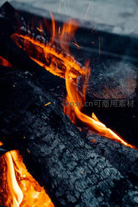 篝火余烬中跳动的橙红火焰与飞溅火星特写
