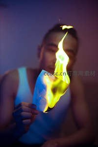 男子手持燃烧纸片，蓝紫光影下火焰升腾，呈现动态与神秘感的创意人像