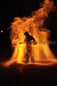火舞者挥洒铁屑制造炽热火花喷泉，夜色中人影与金雨交织成画